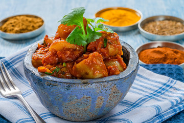 Bombay aloo - Indian spiced potatoes with tomato sauce garnished with fresh coriander leaves.