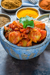 Bombay aloo - Indian spiced potatoes with tomato sauce and minted yogurt, garnished with fresh coriander leaves.