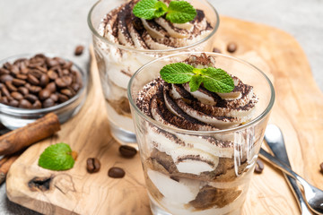 Classic tiramisu dessert in a glass on dark concrete background