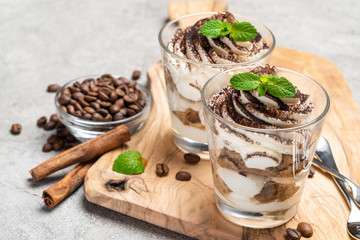 Classic tiramisu dessert in a glass on dark concrete background