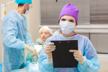 Beautiful portrait of a doctor with documents on the background of the operating room. Baldness...