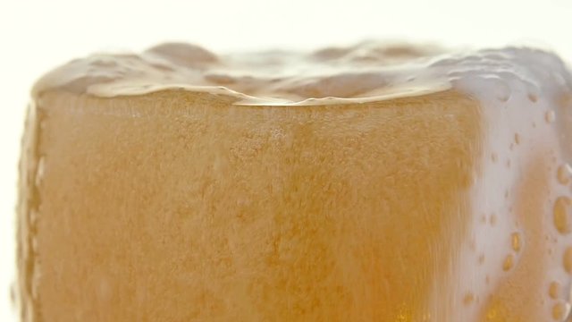 Close up pouring lager beer in glass over white
