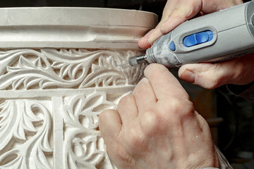 Crop hands carving ornament on plaster