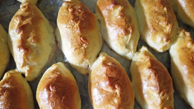 Many traditional delicious baked pasties on tray from oven in bakery. 4K clip with above view