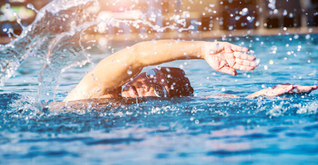 Young athletic man swimming in the swimming pool