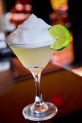 Summer fresh salt foam margarita with  lime garnish on bar top in restaurant 