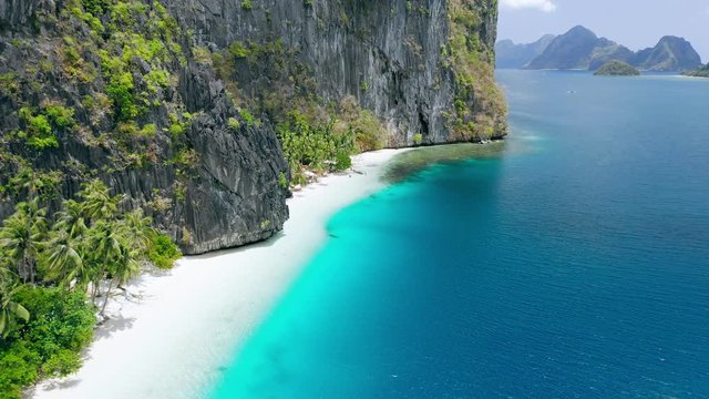 Aerial drone fly footage of pristine tropical white sand beach surrounded by karst rocky cliffs and turquoise sea. Pinagbuyutan Island. El Nido, Palawan, Philippines. Breathtaking destination