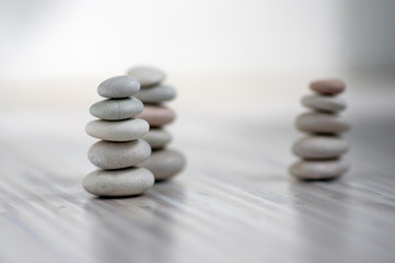 Fototapeta na wymiar Harmony and balance, three cairns, simple poise pebbles on wooden light white gray background, simplicity rock zen sculpture