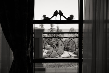 Silhouette of female shoes on a window with a terrace, black and white shot