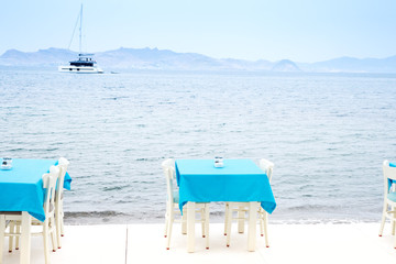 Cafe tables served with a blue tablecloth near the sea coast for relaxing holidays vacations