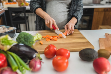 Beautiful smiling young pregnant woman preparing healthy food with lots of fruit and vegetables at home kitchen