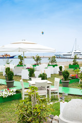 Cafe tables served with a white tablecloth near the sea coast for relaxing holidays vacations