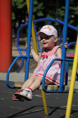 girl in a pink dress in white large polka-dot riding on a swing