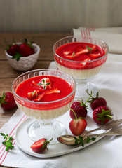 Panna cotta with strawberry sauce and strawberry slices, decorated with thyme leaves. Rustic style.