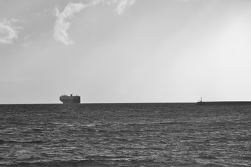 The mediterranean sea. Container ship within the horizon line and pier. In the Messinian Bay in Kalamata, Peloponnese, Greece, Europe.