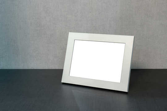 white photo frame horizontally stands on the shelf in the living room, minimalism in the interior of the house, mock-up