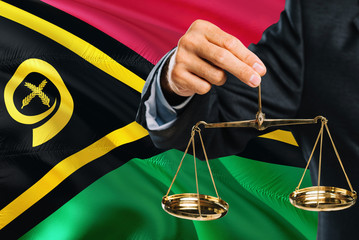 Judge is holding golden scales of justice with Vanuatu waving flag background. Equality theme and...
