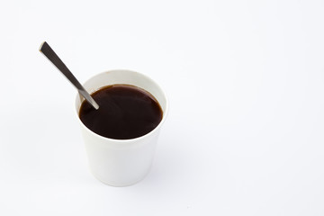 Paper cup of black coffee with spoon on white background