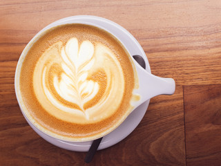 Overhead photo of a freshly brewed Cappuccino with a nice decoration on top sat on top of a wooden...