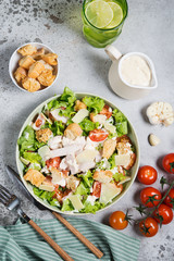 Caesar salad with chicken breast on gray background 