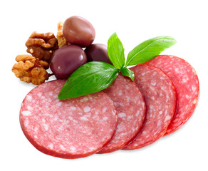 Four thin-cut pieces of smoked sausage with a sprig of basil, burgundy olives and walnuts. Isolated close up.