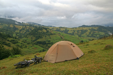 Green tent and two bicycles on a background of mountains