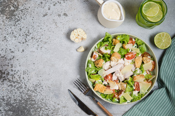 Caesar salad with chicken breast on gray background copy space