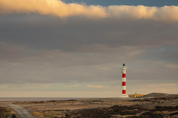 The lighthouse on the stone promontory, a colorful place on the island of Tenerife. Atlantic Ocean