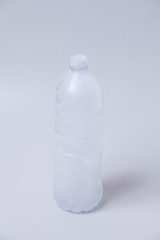 Frozen water in plastic drink water bottle on gray