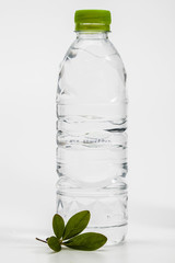 Green leaf with plastic drinking water bottle on white