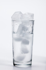 Glass of cold ice water with green leaf on white background