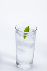 Glass of cold ice water with green leaf on white background