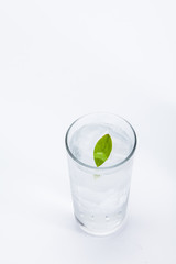 Glass of cold ice water with green leaf on white background