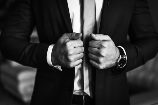 Man in business suit. A man puts on a suit. Close-up business stylish man buttoning his jacket. A businessman in an expensive suit.  Black and white photo