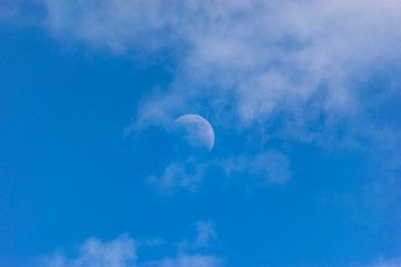 blue sky with clouds and half moon