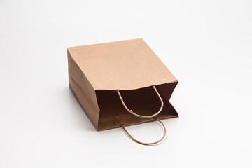 Empty open brown craft paper shopping bag lying on white 