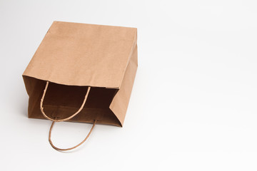 Empty open brown craft paper shopping bag lying on white 