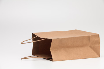 Empty open brown craft paper shopping bag lying on white 