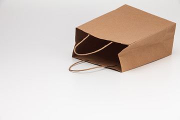 Empty open brown craft paper shopping bag lying on white 