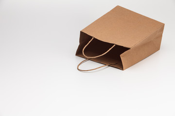 Empty open brown craft paper shopping bag lying on white 