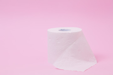The roll of white toilet tissue paper on pink background