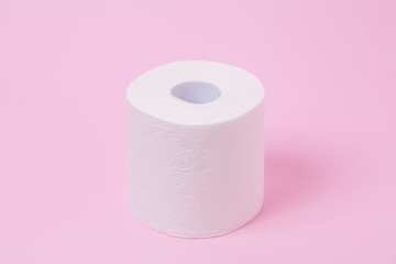 The roll of white toilet tissue paper on pink background