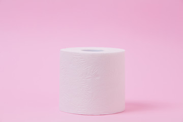 The roll of white toilet tissue paper on pink background