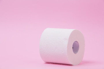 The roll of white toilet tissue paper on pink background