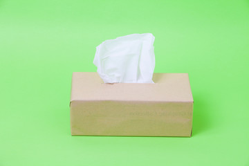 Eco box paper tissues with one sticking from the top on green background