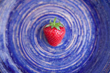 One berry of ripe strawberry on a bright blue dish. Healthy eating concept. Flat lay