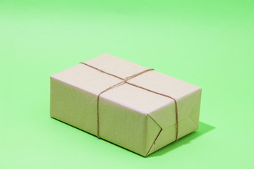 Obraz premium Brown eco kraft gift wrapped box on strong green background 