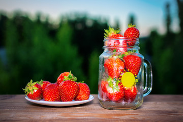 Strawberries in glass bowl on nature background