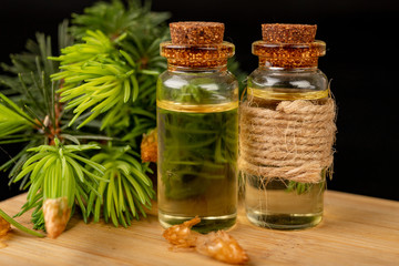 Young shoots of spruce and oil in a glass dish. Ecological preparations on a wooden board.