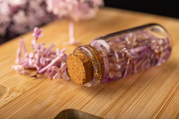 Lilac flowers and essential oil in a glass vessel. Ecological preparations on a wooden board.